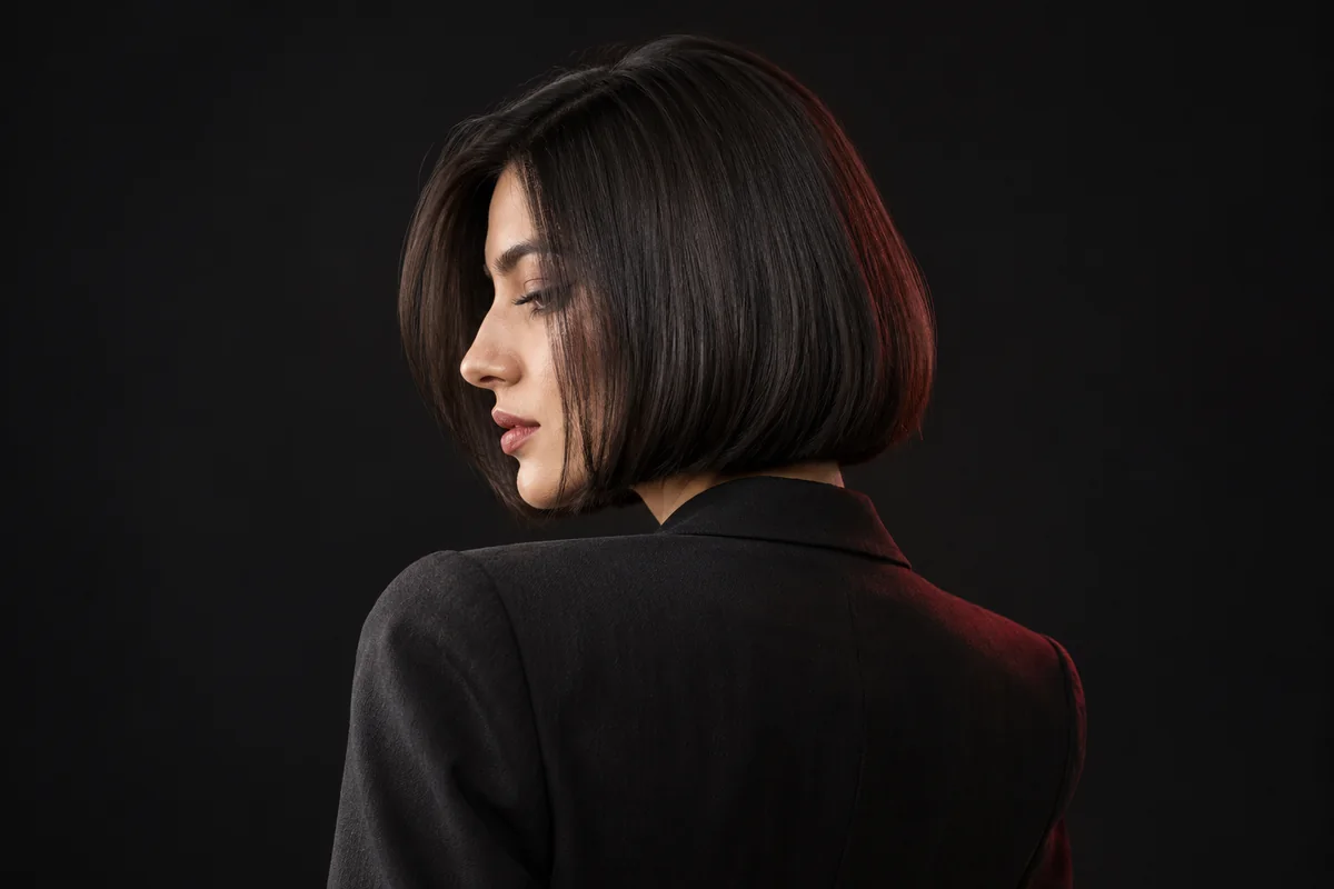 Three-quarter rear view of a precise glossy dark bob with a softly curved outline