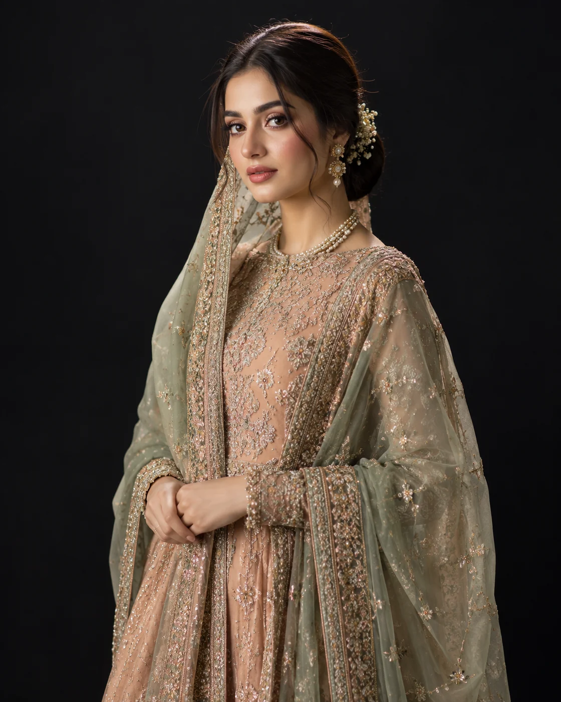 Young woman in a peach nikah outfit and sage dupatta with soft rose makeup and a low bun